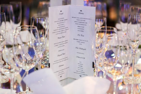 Cardápio impresso detalhando as opções do buffet de casamento posicionado entre taças de cristal.